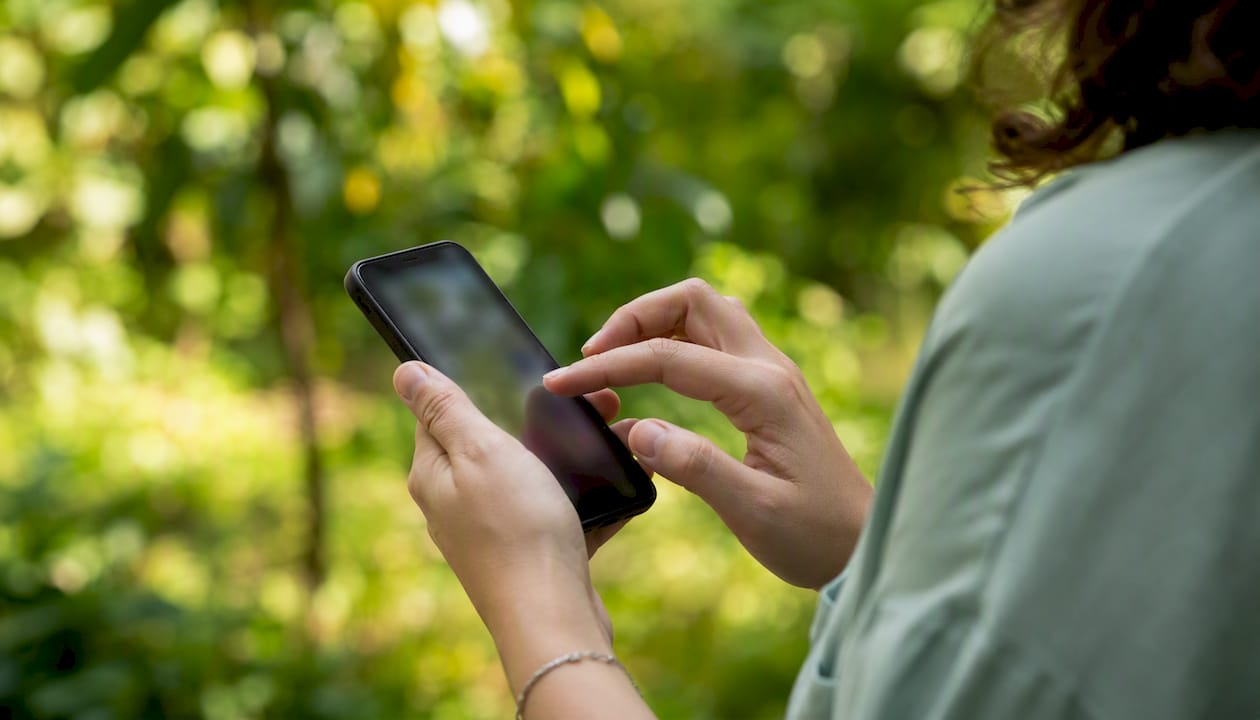 CBD shop meilleur : la sélection fiable pour acheter en ligne - Pure Extract CBD Eine Hand scrollt über den Bildschirm eines Smartphones, das im Tageslicht liegt.