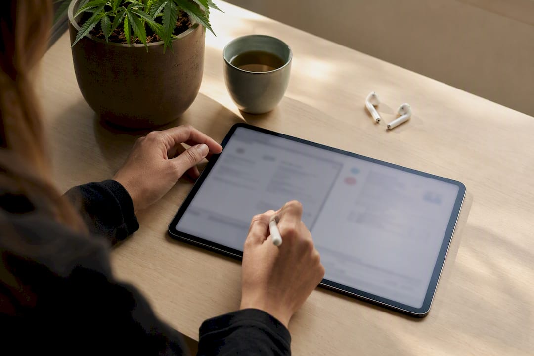 Hände sortieren und ordnen CBD-Laborzertifikate auf digitalen Geräten.